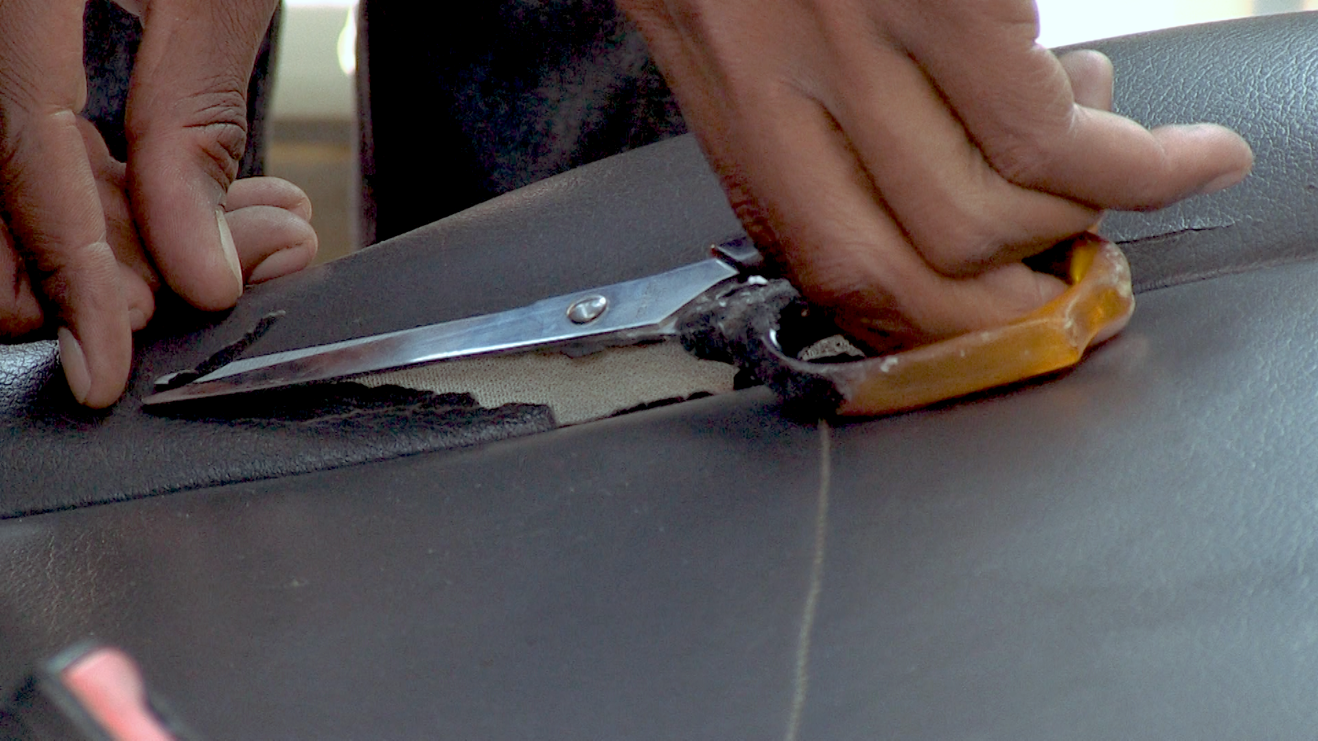 A person cutting a piece of leather

Description automatically generated